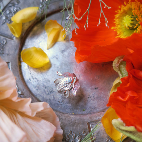 Silver goldfish ring with flowers – mood photo.
